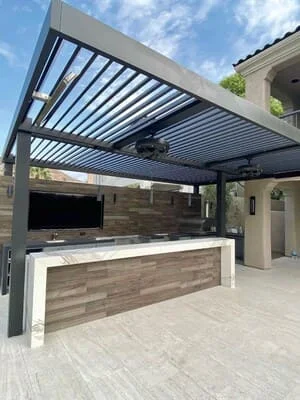 Louvered pergola with outdoor kitchen counter and paved patio