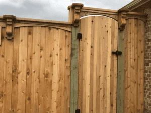 Cedar privacy fence with vertical boards, post caps, and black hardware on residential property