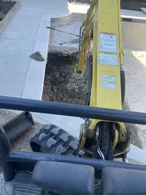 Retaining wall construction with compacted soil base and drainage system installation