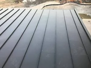 Standing seam metal roof with parallel dark gray panels and visible seam lines