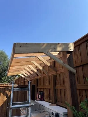 Wooden pergola with shade canopy attached to house, exposed beam construction
