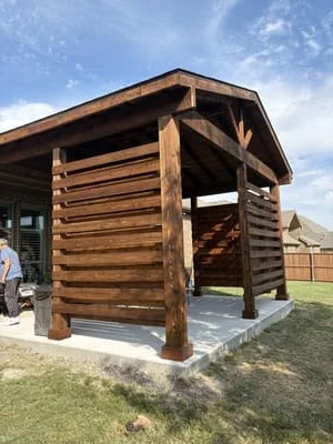 Rustic log pavilion with stacked timber walls, exposed beams, and gabled roof