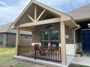 Timber-frame covered patio with peaked roof and composite deck attached to brick home