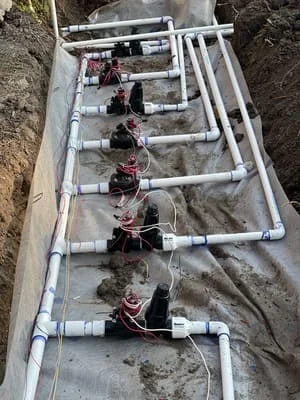 Underground irrigation valve boxes with PVC piping and drip line connections installed in soil