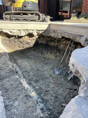 Excavated foundation pit with concrete forms and compacted base, tracked equipment visible