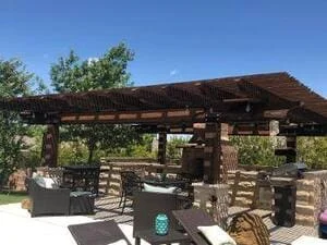 Timber pergola with stone columns and outdoor seating under clear sky