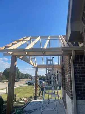 Wooden pergola frame with angled beams attached to brick home exterior