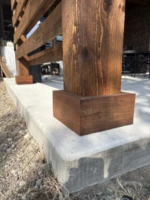 Timber post mounted on concrete foundation pad with gravel base