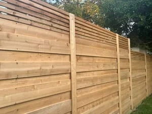 Horizontal cedar wood privacy fence with vertical posts and evenly spaced boards