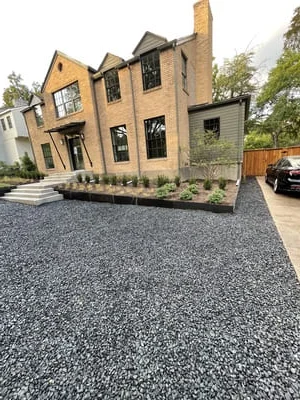 Aggregate driveway with stone edging and landscape plantings at modern home