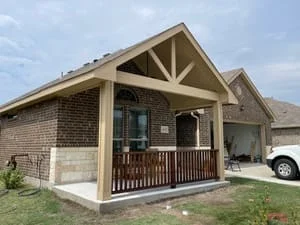 Front porch with timber frame, wooden deck railing, and new sod landscaping