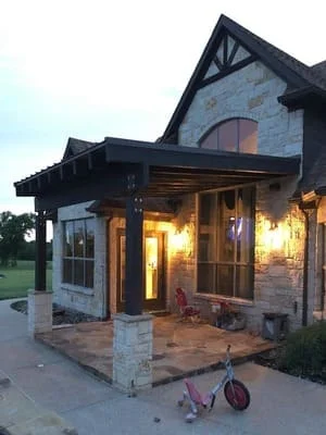 Stone paver patio with columns and landscape lighting at dusk