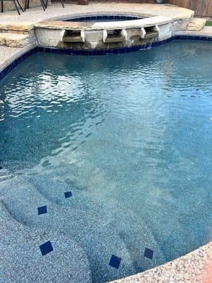 In-ground pool with raised spa, blue tile accents, and stone coping