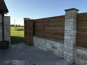 Horizontal wood fence with stone veneer pillars and wooden gate
