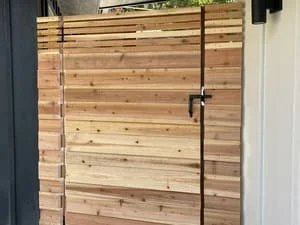 Horizontal wood privacy gate with cedar slats and metal hardware mounted at entrance