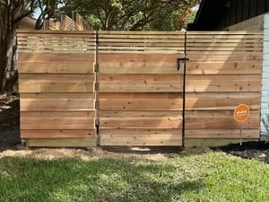 Horizontal cedar privacy fence with metal frame and gate installed along property line