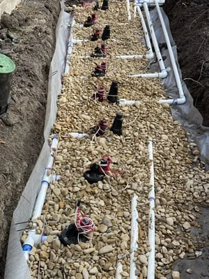 Raised metal garden beds with gravel fill and drip irrigation lines installed