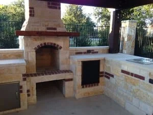 Stone pizza oven and outdoor kitchen with grill station under covered patio